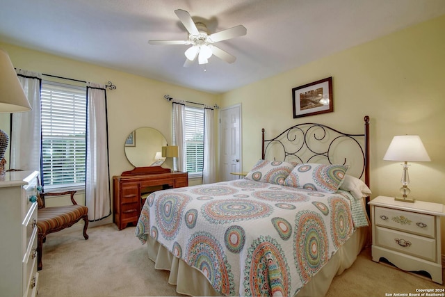 bedroom with ceiling fan, light colored carpet, and multiple windows