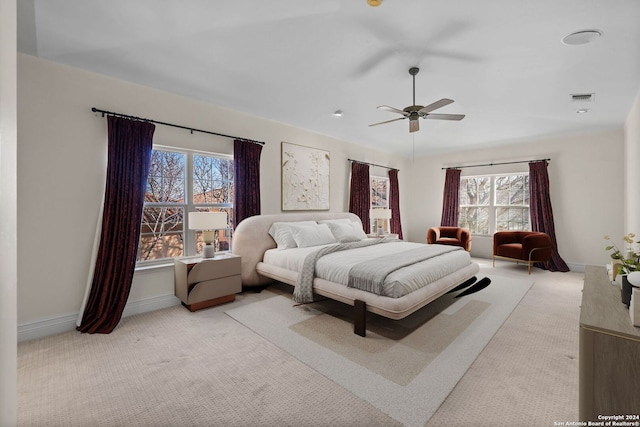 bedroom with multiple windows, light colored carpet, and ceiling fan