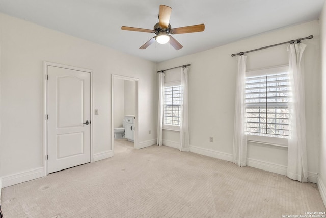 unfurnished bedroom featuring ceiling fan, light carpet, and ensuite bath