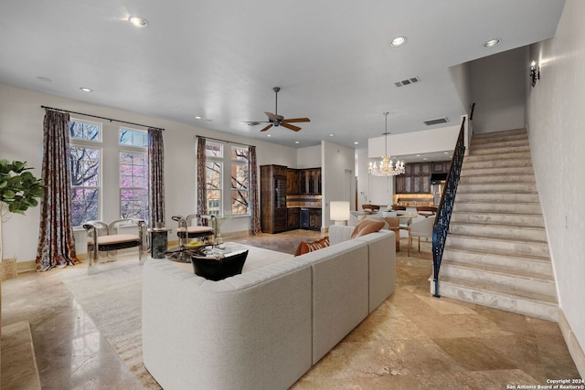 living room with ceiling fan with notable chandelier