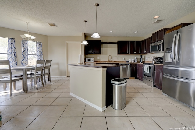 kitchen with a kitchen island, pendant lighting, a textured ceiling, light tile patterned floors, and appliances with stainless steel finishes