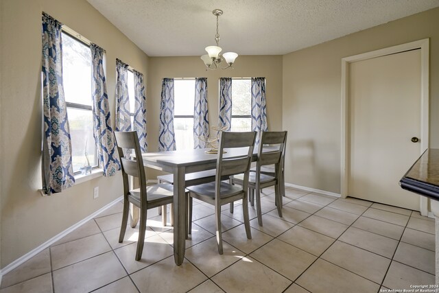 tiled dining area with a chandelier and a textured ceiling