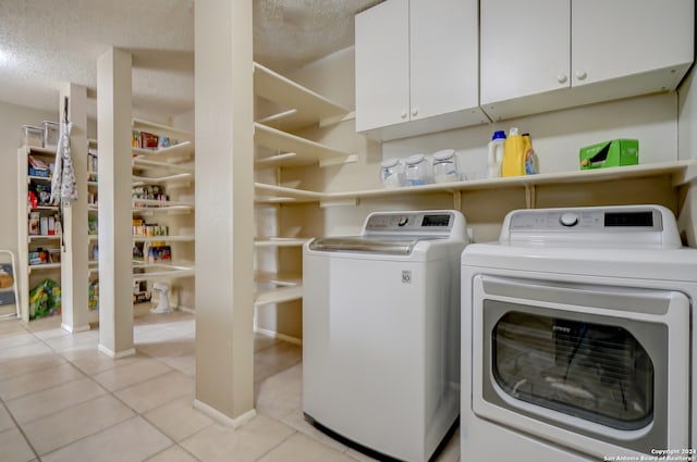 washroom with cabinets, light tile patterned floors, a textured ceiling, and washing machine and clothes dryer