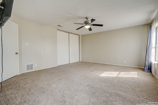 carpeted spare room with ceiling fan and a textured ceiling