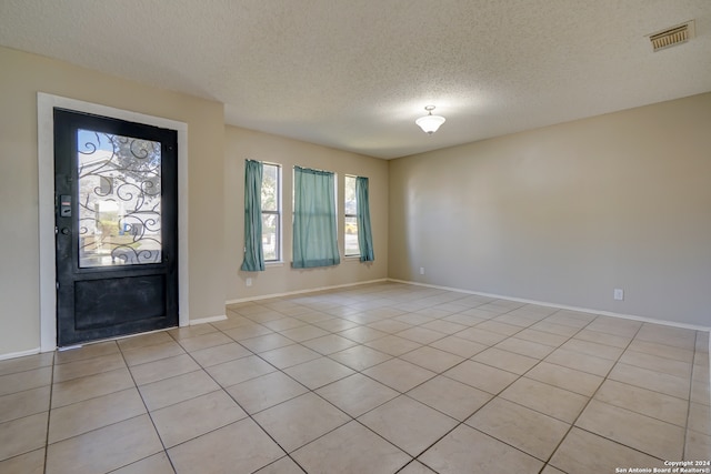 foyer entrance featuring visible vents, a textured ceiling, baseboards, and light tile patterned flooring