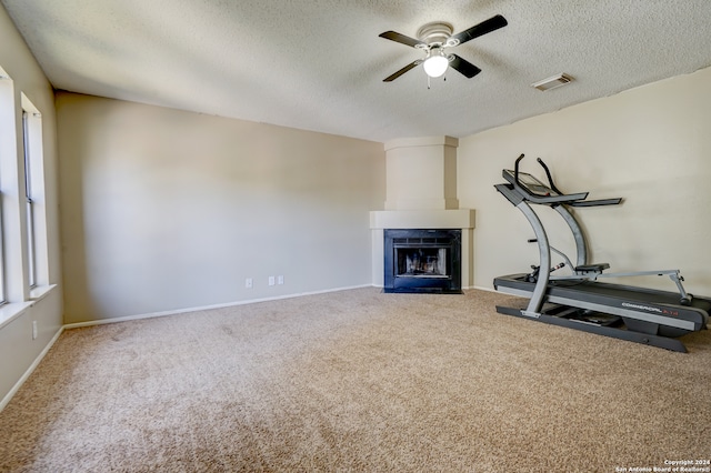 exercise room featuring a textured ceiling, carpet floors, and a fireplace