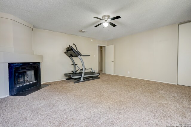 workout area with a textured ceiling, carpet floors, and ceiling fan