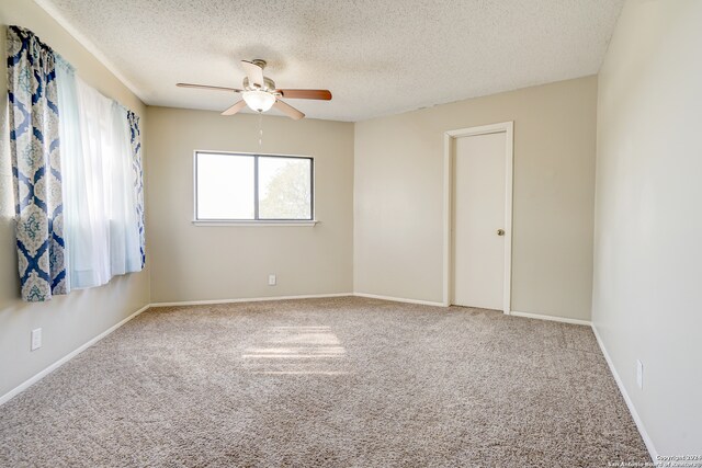 empty room with carpet flooring, ceiling fan, and a textured ceiling