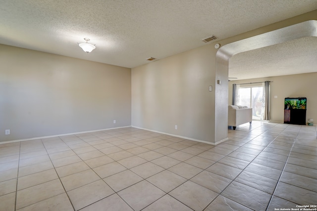 tiled spare room featuring a textured ceiling