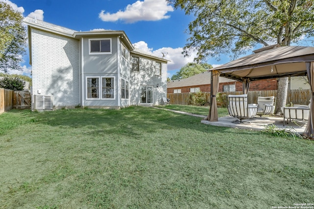 rear view of house featuring a gazebo, central AC unit, a patio area, and a lawn