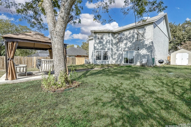 rear view of house with a gazebo, a lawn, and a storage shed