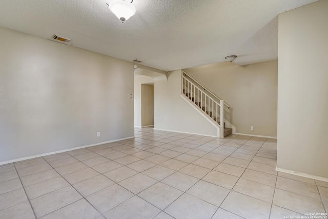 spare room featuring light tile patterned flooring and a textured ceiling