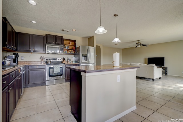 kitchen featuring stainless steel appliances, a kitchen island, pendant lighting, a textured ceiling, and light tile patterned floors