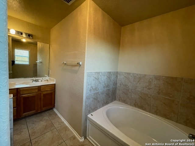 bathroom with tile patterned flooring, a washtub, and vanity