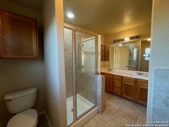 bathroom featuring tile patterned flooring, a textured ceiling, toilet, vanity, and a shower with shower door