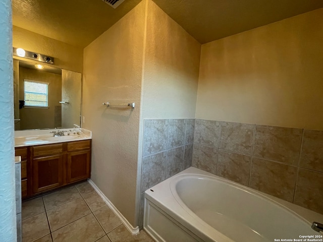 bathroom with tile patterned floors, vanity, a tub to relax in, and a textured ceiling