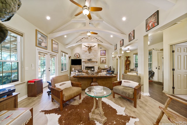 living room with a large fireplace, ceiling fan, light hardwood / wood-style flooring, and french doors