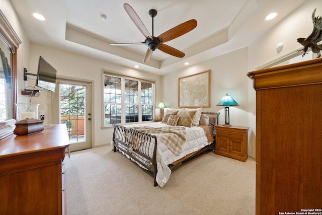 bedroom featuring access to outside, ceiling fan, a tray ceiling, and light carpet