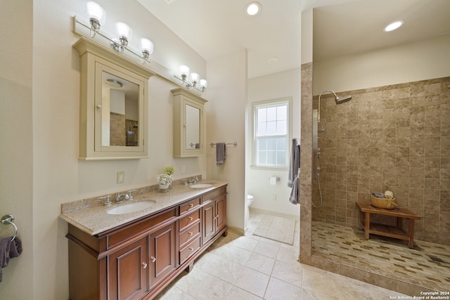 bathroom with tile patterned floors, vanity, toilet, and tiled shower