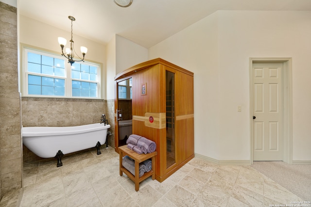 bathroom featuring a chandelier, lofted ceiling, tile walls, and a tub