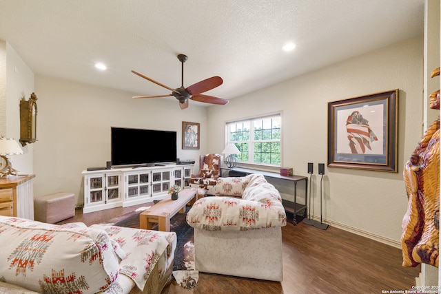 living room featuring ceiling fan, dark wood-type flooring, and a textured ceiling