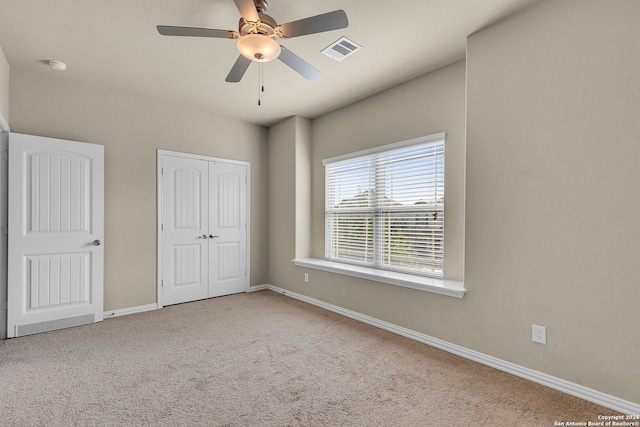 unfurnished bedroom with ceiling fan, light carpet, and a closet