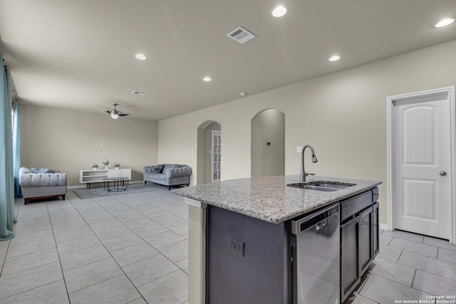 kitchen with a center island with sink, sink, stainless steel dishwasher, ceiling fan, and light stone counters