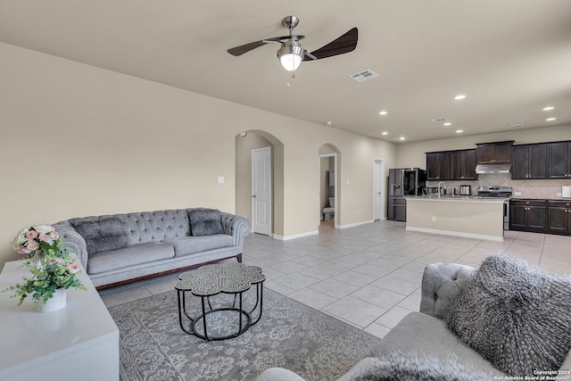 tiled living room with ceiling fan and sink