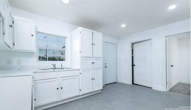 kitchen featuring light stone counters, white cabinetry, and sink