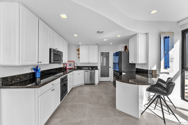 kitchen with black appliances, white cabinets, dark stone countertops, and a breakfast bar area