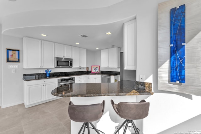 kitchen featuring white cabinets, a breakfast bar, kitchen peninsula, and appliances with stainless steel finishes