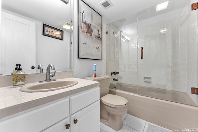 full bathroom with tile patterned flooring, vanity, bath / shower combo with glass door, and toilet