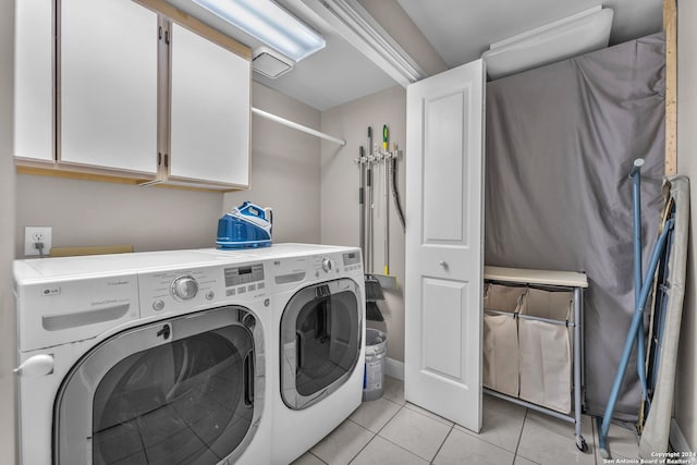 clothes washing area with washer and dryer, light tile patterned flooring, and cabinets