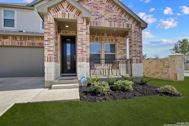 view of front of property with covered porch, a front yard, and a garage