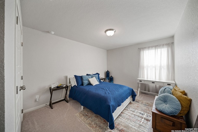 bedroom with light colored carpet and a textured ceiling