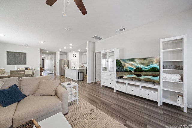 living room with ceiling fan, sink, and dark wood-type flooring