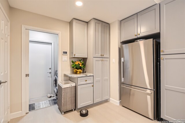 kitchen with gray cabinets, stainless steel fridge, and light stone countertops