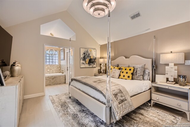 bedroom featuring ensuite bathroom, high vaulted ceiling, and light hardwood / wood-style floors