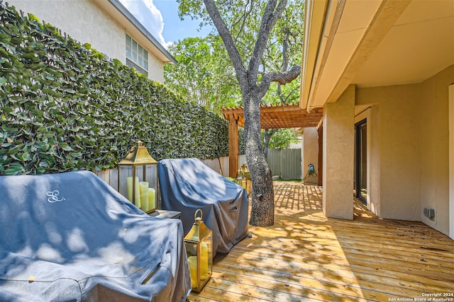 wooden deck featuring area for grilling and a pergola