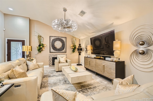 living room featuring a tile fireplace, a chandelier, and vaulted ceiling