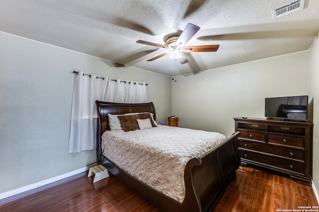 bedroom with ceiling fan, dark wood-type flooring, and a textured ceiling