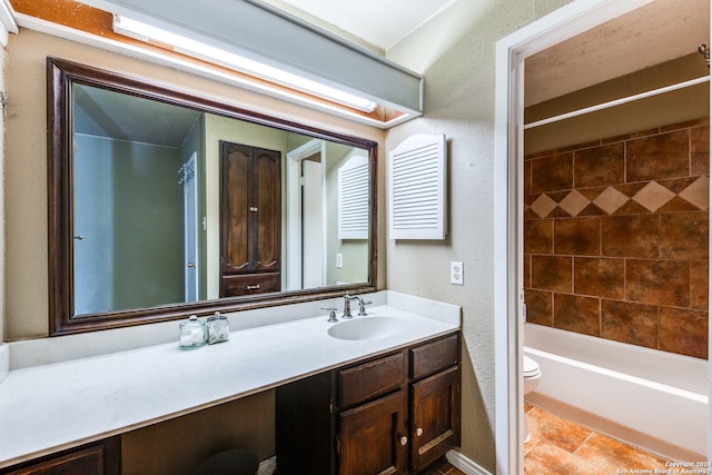 full bathroom featuring tile patterned floors, vanity, toilet, and tiled shower / bath combo