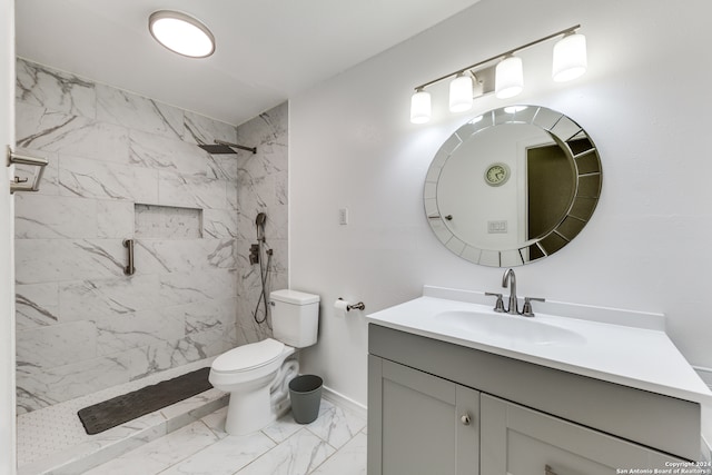 bathroom featuring a tile shower, vanity, and toilet