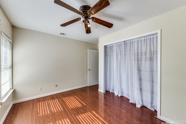 unfurnished bedroom featuring multiple windows, ceiling fan, and dark hardwood / wood-style flooring