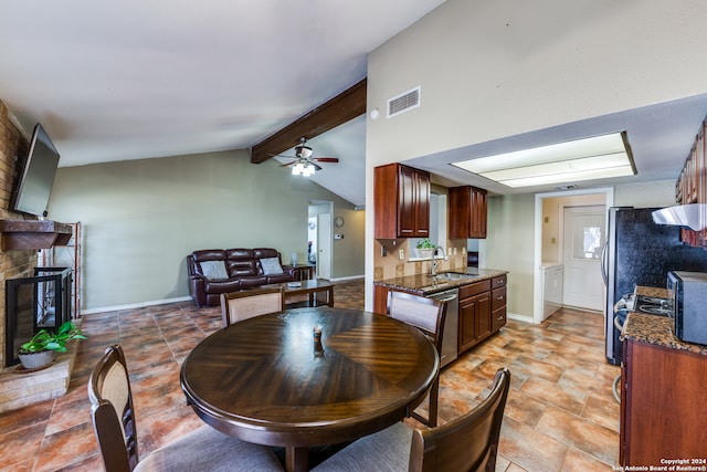 dining space with lofted ceiling with beams, ceiling fan, sink, and a brick fireplace