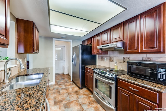 kitchen featuring dark stone counters, sink, decorative backsplash, a textured ceiling, and appliances with stainless steel finishes