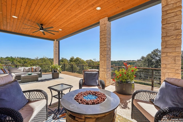 view of patio featuring ceiling fan, a balcony, and an outdoor living space with a fire pit