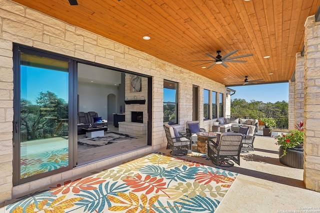 view of patio with an outdoor living space with a fireplace and ceiling fan