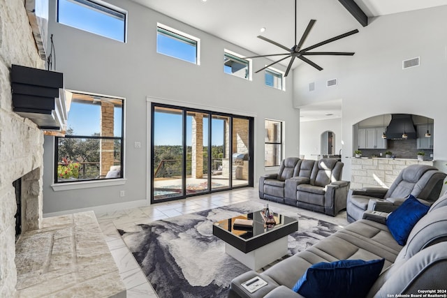 living room with beamed ceiling, high vaulted ceiling, ceiling fan, and a stone fireplace