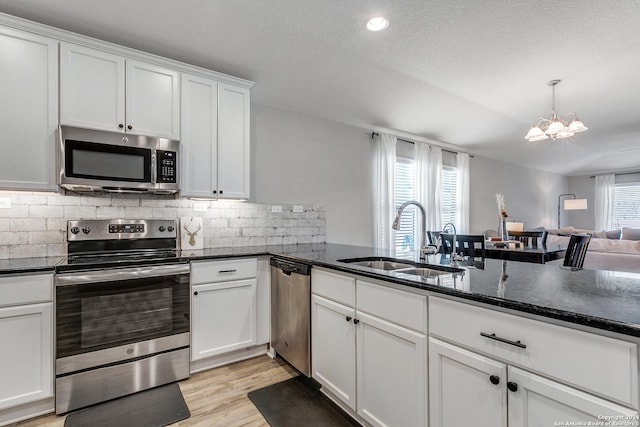 kitchen with sink, stainless steel appliances, a chandelier, white cabinets, and light wood-type flooring